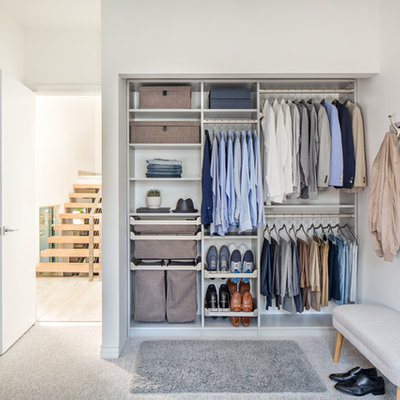 Small elegant men's carpeted and gray floor reach-in closet photo with open cabinets and dark wood cabinets