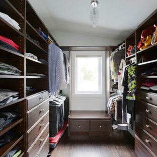 Foto di una cabina armadio unisex classica di medie dimensioni con ante con bugna sagomata, ante in legno scuro e parquet scuro
