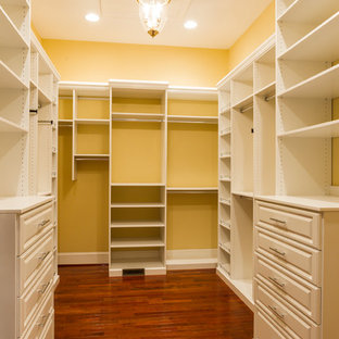 Ispirazione per una grande cabina armadio unisex chic con ante bianche e parquet scuro