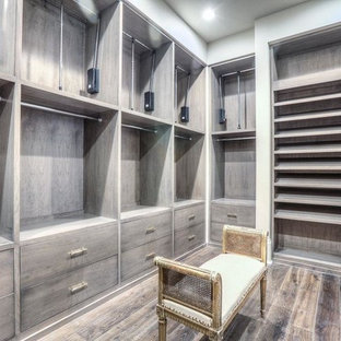 Großes, Neutrales Klassisches Ankleidezimmer mit Ankleidebereich, flächenbündigen Schrankfronten, braunem Holzboden und grauen Schränken in Houston
