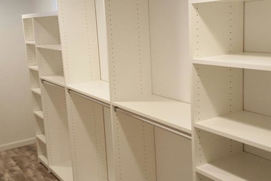 Imagen de armario vestidor unisex clásico renovado pequeño con armarios abiertos, puertas de armario blancas y suelo de madera clara