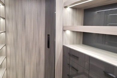 Diseño de armario vestidor unisex minimalista grande con armarios con paneles lisos, puertas de armario grises, suelo de baldosas de porcelana y suelo beige