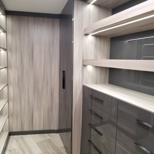 Diseño de armario vestidor unisex, minimalista, grande, con armarios con paneles lisos, puertas de armario grises, suelo de baldosas de porcelana y suelo beige