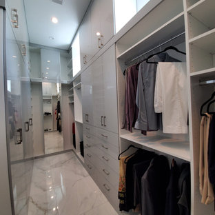 Ejemplo de armario vestidor unisex, minimalista, grande, con armarios con paneles lisos, puertas de armario blancas, suelo de mármol y suelo blanco