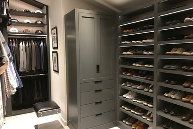 Ejemplo de vestidor de hombre actual grande con armarios con paneles lisos, puertas de armario grises, moqueta y suelo beige
