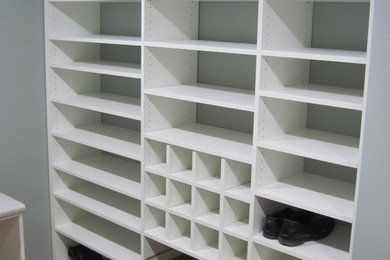 Diseño de armario vestidor unisex tradicional de tamaño medio con armarios abiertos, puertas de armario blancas y suelo de madera oscura