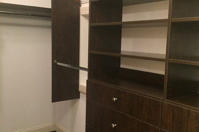 Ejemplo de armario vestidor unisex minimalista de tamaño medio con armarios con paneles lisos, puertas de armario de madera en tonos medios y suelo de madera oscura
