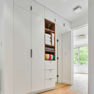Ispirazione per un armadio o armadio a muro unisex design di medie dimensioni con ante bianche, ante lisce, pavimento beige e parquet chiaro