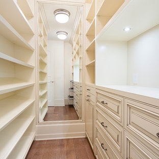 Foto de armario vestidor unisex, clásico, con armarios con paneles con relieve, puertas de armario con efecto envejecido y suelo de madera en tonos medios
