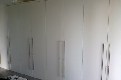 Mid-sized minimalist gender-neutral reach-in closet photo in Other with flat-panel cabinets and white cabinets