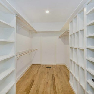 Imagen de armario y vestidor campestre con puertas de armario blancas y suelo de madera en tonos medios
