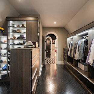 Modelo de armario vestidor de hombre, clásico renovado, grande, con armarios abiertos, puertas de armario de madera en tonos medios, suelo negro y suelo de madera oscura