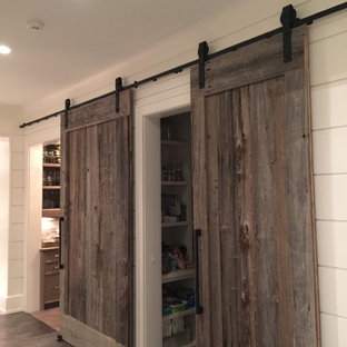 Diseño de armario vestidor unisex, de estilo de casa de campo, con armarios abiertos, puertas de armario blancas y suelo de madera en tonos medios