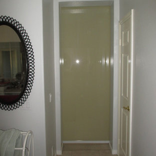 Diseño de vestidor unisex, moderno, de tamaño medio, con armarios tipo vitrina, puertas de armario grises, moqueta y suelo beige