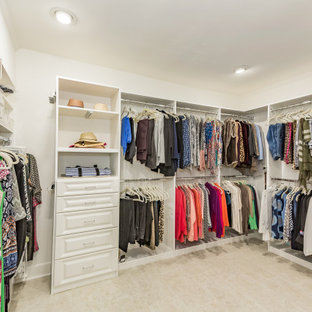 Modelo de vestidor de mujer, ecléctico, grande, con armarios con paneles con relieve, puertas de armario blancas, suelo de travertino y suelo beige