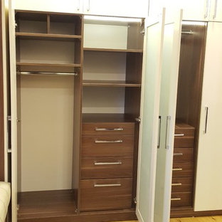 Esempio di un grande spazio per vestirsi unisex minimalista con ante di vetro, ante in legno scuro, pavimento in laminato e pavimento giallo
