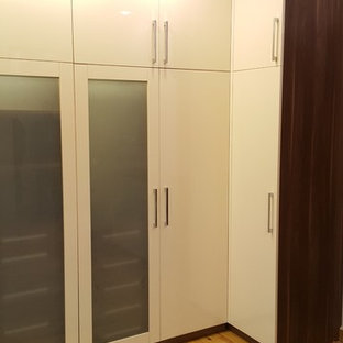 Foto di un grande spazio per vestirsi unisex minimalista con ante di vetro, ante in legno scuro, pavimento in laminato e pavimento giallo