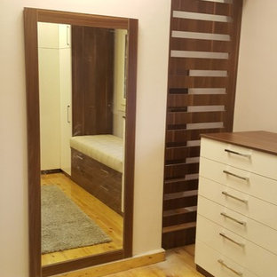 Ispirazione per un grande spazio per vestirsi unisex moderno con ante di vetro, ante in legno scuro, pavimento in laminato e pavimento giallo