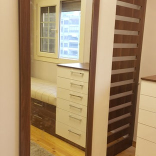 Esempio di un grande spazio per vestirsi unisex moderno con ante di vetro, ante in legno scuro, pavimento in laminato e pavimento giallo