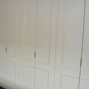 Imagen de vestidor bohemio, grande, con puertas de armario blancas y suelo de madera oscura