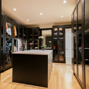 Imagen de vestidor minimalista, grande, con armarios tipo vitrina, puertas de armario de madera en tonos medios y suelo de madera clara