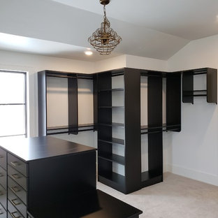 Ejemplo de armario vestidor unisex, clásico renovado, con armarios con paneles lisos, puertas de armario negras, moqueta y suelo beige