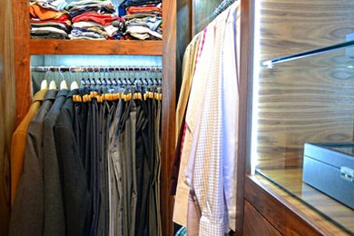 Foto de armario vestidor de hombre moderno con puertas de armario de madera en tonos medios y suelo de madera en tonos medios