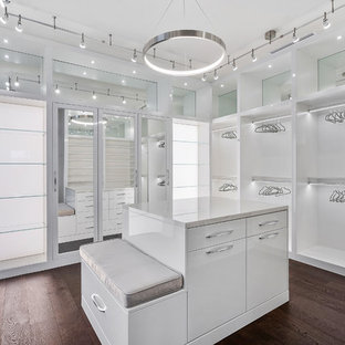 Imagen de vestidor unisex, minimalista, grande, con armarios con paneles lisos, puertas de armario blancas, suelo de madera en tonos medios y suelo marrón