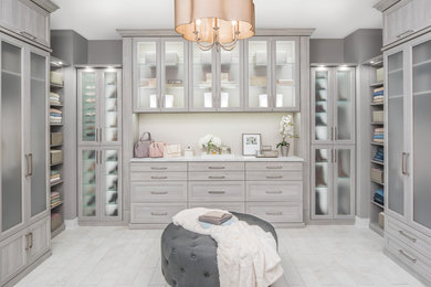 Large contemporary gender neutral walk-in wardrobe in Las Vegas with glass-front cabinets, grey cabinets, marble flooring and beige floors.
