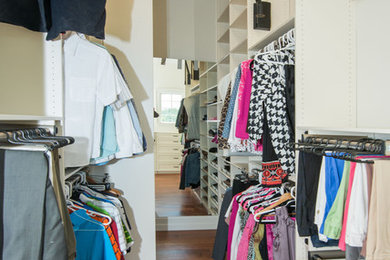 Imagen de armario vestidor unisex clásico grande con armarios abiertos, puertas de armario blancas y suelo marrón