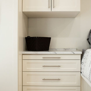 Immagine di una cabina armadio unisex tradizionale di medie dimensioni con ante in stile shaker, ante beige, pavimento in legno massello medio e pavimento giallo