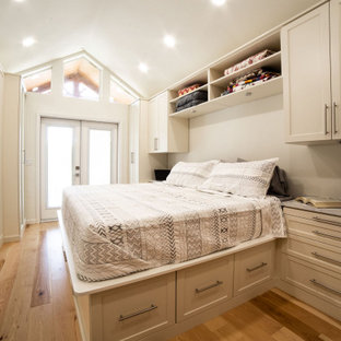 Inredning av ett klassiskt mellanstort walk-in-closet för könsneutrala, med skåp i shakerstil, beige skåp, mellanmörkt trägolv och gult golv