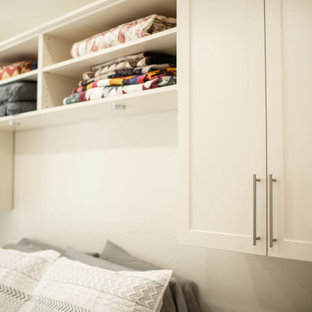 Immagine di una cabina armadio unisex tradizionale di medie dimensioni con ante in stile shaker, ante beige, pavimento in legno massello medio e pavimento giallo