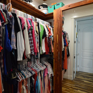 Imagen de armario vestidor de mujer, rústico, grande, con armarios abiertos, puertas de armario con efecto envejecido, suelo de madera oscura y suelo marrón