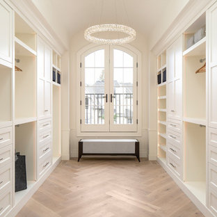 Ejemplo de armario vestidor unisex, tradicional renovado, con armarios con paneles empotrados, puertas de armario blancas y suelo de madera clara