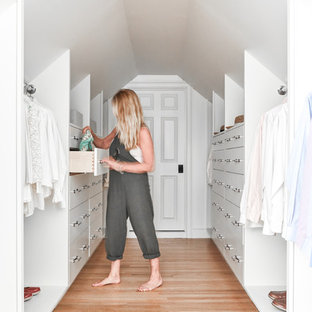 Transitional gender-neutral light wood floor and beige floor walk-in closet photo in Portland Maine with flat-panel cabinets and white cabinets