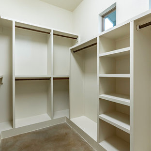 Imagen de armario vestidor unisex, clásico renovado, grande, con armarios abiertos, puertas de armario blancas, suelo de cemento y suelo marrón
