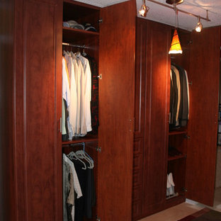 Diseño de armario vestidor de hombre, tradicional, de tamaño medio, con armarios con paneles con relieve, puertas de armario de madera en tonos medios y suelo de baldosas de cerámica