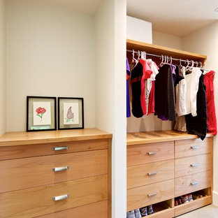 Immagine di un grande armadio o armadio a muro unisex moderno con ante lisce, ante in legno chiaro e pavimento in cemento