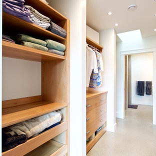 Ejemplo de armario vestidor unisex, moderno, grande, con armarios con paneles lisos, puertas de armario de madera clara y suelo de cemento