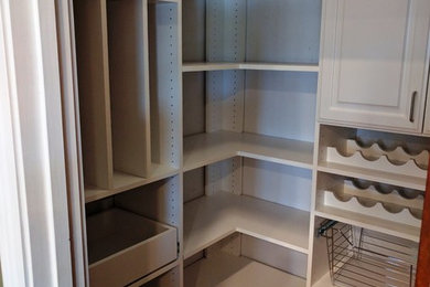 Design ideas for a medium sized traditional gender neutral walk-in wardrobe in Cincinnati with raised-panel cabinets, white cabinets and medium hardwood flooring.