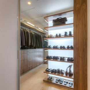 Foto di un'ampia cabina armadio unisex minimalista con ante lisce, ante in legno scuro e parquet chiaro