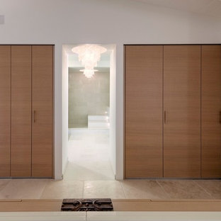 Foto di un grande spazio per vestirsi per uomo design con ante lisce, ante in legno scuro, pavimento in pietra calcarea e pavimento beige