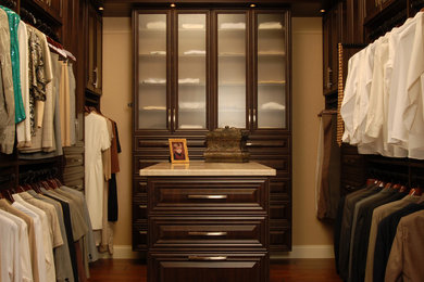 Walk-in closet - mid-sized traditional gender-neutral dark wood floor walk-in closet idea in Orlando with raised-panel cabinets and dark wood cabinets