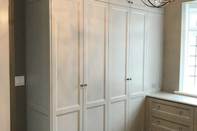 Inspiration for a large timeless gender-neutral medium tone wood floor and brown floor dressing room remodel in New York with recessed-panel cabinets and gray cabinets