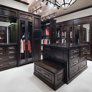 Cette image montre un très grand dressing room traditionnel neutre avec des portes de placard en bois sombre.