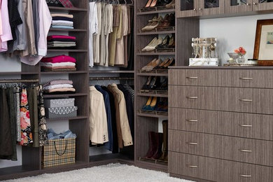 This is an example of a large classic walk-in wardrobe for women in Seattle with flat-panel cabinets, brown cabinets and carpet.