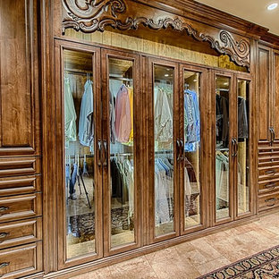Idee per una grande cabina armadio per uomo chic con ante di vetro, ante in legno scuro e pavimento in marmo