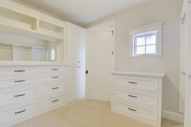На фото: большая гардеробная комната в классическом стиле с фасадами с утопленной филенкой, белыми фасадами, ковровым покрытием и коричневым полом с