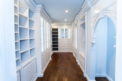 Example of a large tuscan women's medium tone wood floor walk-in closet design in DC Metro with white cabinets and glass-front cabinets